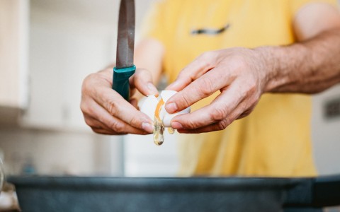 a person breaking an egg with a knife