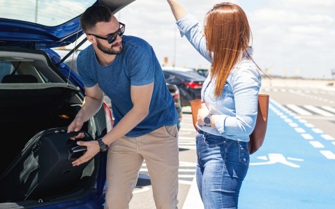 a man and woman looking at the trunk of a car