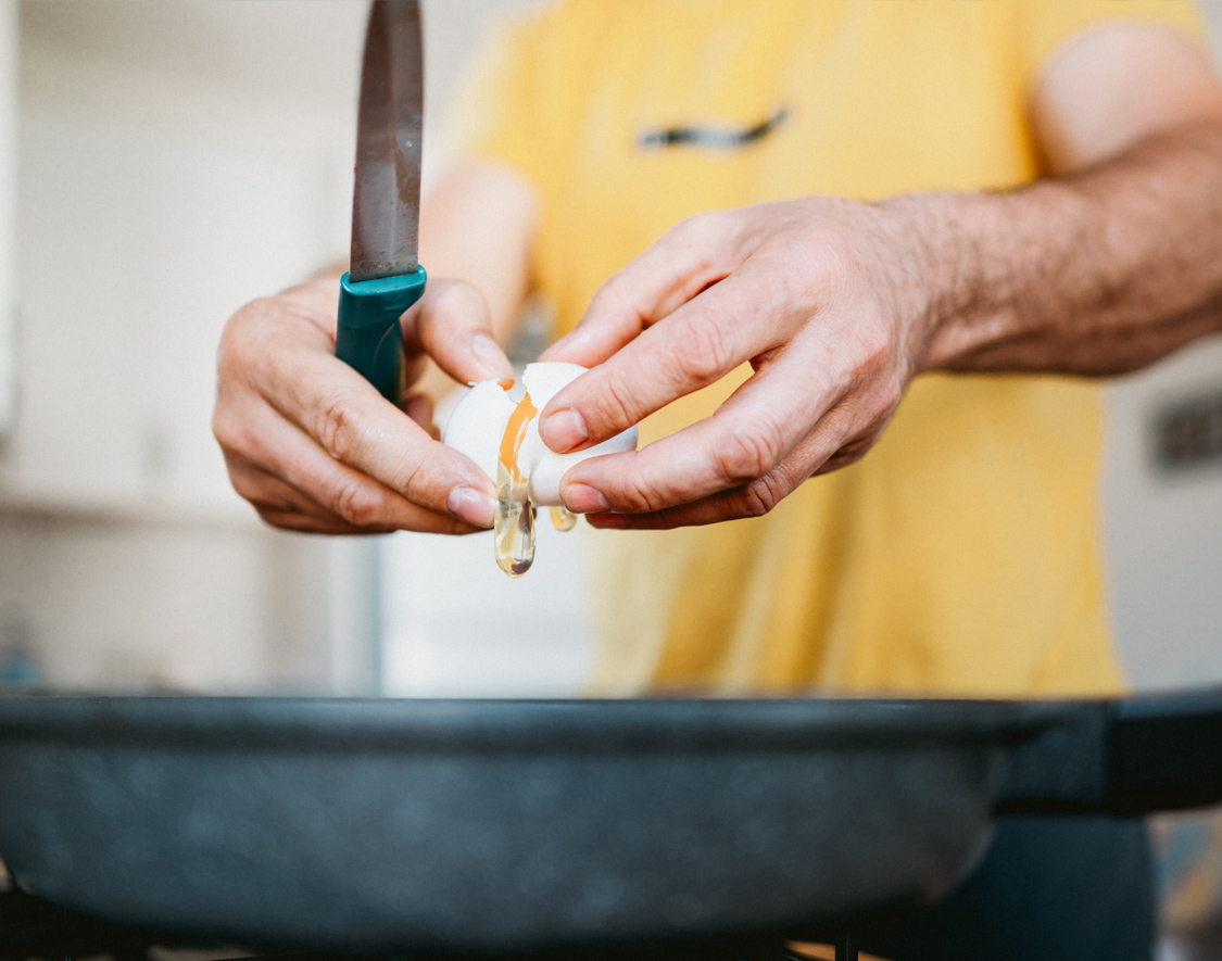 a person breaking an egg with a knife